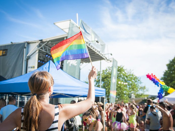Girl waving a pride flag in Davie Street in Vancouver