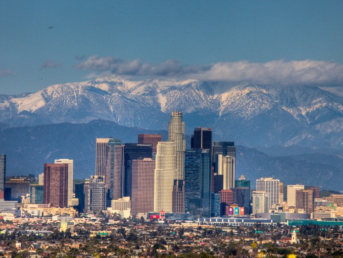 Downtown Los Angeles buildings with mountains covered in snow behind
