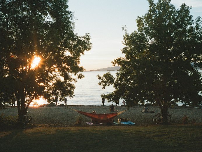 People on hammock at Kitsilano Beach Park during sunset in the summer