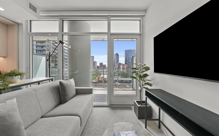 open concept studio living area with mounted tv and door opening to balcony at level chicago fulton market
