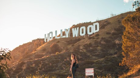 Girl stands with dog in front of a sign that says "Hollywood"